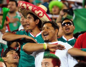 Aficionados mexicanos cantando el himno con la mano en el pecho